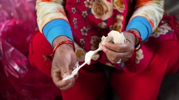View of a woman processing white cotton fibers in Dhangadhi Nepal. View of a woman processing white cotton fibers in Dhangadhi Nepal.