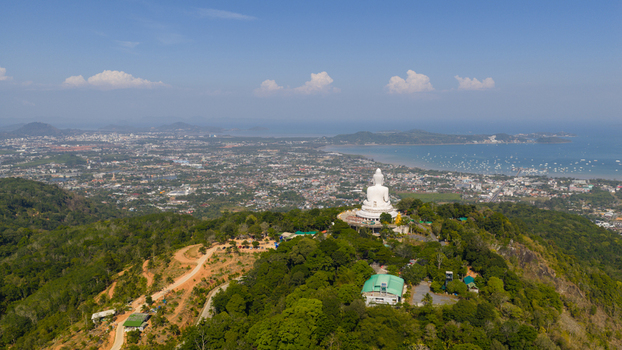 Aerial view of the Big Buddha Phuket statue on a lush green hilltop overlooking the coastal city and the blue sea Karon Phuket Thailand. Aerial view of the Big Buddha Phuket statue on a lush green hilltop overlooking the coastal city and the blue sea Karon Phuket Thailand.