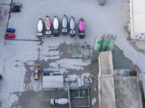 Aerial view of a concrete plant featuring a row of parked cement mixer trucks industrial silos and storage facilities in Krakow Lesser Poland Voivode Poland. Aerial view of a concrete plant featuring a row of parked cement mixer trucks industrial silos and storage facilities in Krakow Lesser Poland Voivode Poland.