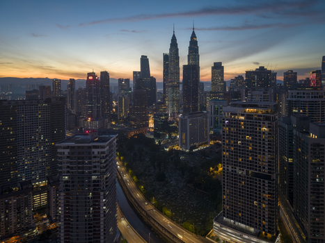 Kuala Lumpur Malaysia 11 March 2026 Aerial view of the Petronas Twin Towers and the illuminated city skyline under a twilight sky with orange and blue hues.