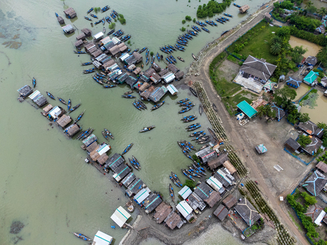 Aerial view of Kalabagi village with stilt houses and numerous wooden boats docked along the riverbank in Khulna District Khulna Division Bangladesh.