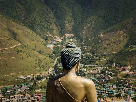Aerial view of the Great Buddha Dordenma statue overlooking the valley with its lush green mountains and distant buildings Thimphu Bhutan.