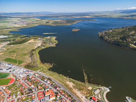 Aerial view of Oravska priehrada reservoir with the town of Namestovo green hills and distant mountains under a clear blue sky in Namestovo Zilinsky kraj Slovakia. Aerial view of Oravska priehrada reservoir with the town of Namestovo green hills and distant mountains under a clear blue sky in Namestovo Zilinsky kraj Slovakia.