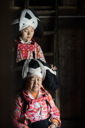 Gaoxing China 30 April 2026 View of two women of the Long Horn Miao ethnic group wearing traditional elaborate headpieces and colorful embroidered clothing in a dimly lit interior. Gaoxing China 30 April 2026 View of two women of the Long Horn Miao ethnic group wearing traditional elaborate headpieces and colorful embroidered clothing in a dimly lit interior.