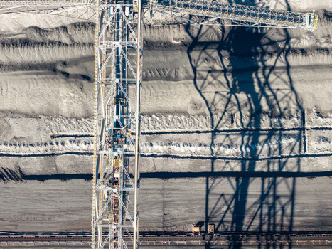 Aerial view of Tagebau Welzow Sud brown coal open pit mine featuring a massive bucket wheel excavator casting a long shadow over the textured earth in Spremberg Brandenburg Germany. Aerial view of Tagebau Welzow Sud brown coal open pit mine featuring a massive bucket wheel excavator casting a long shadow over the textured earth in Spremberg Brandenburg Germany.