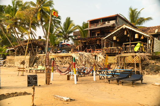 View of beachfront bars and restaurants with thatched roofs hammocks and palm trees on a sandy shore in Galle Southern Province Sri Lanka.