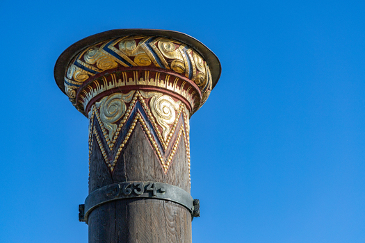 View of the ornate gold and red carvings on the Stormflodssojlen flood column against a clear blue sky in Ribe Denmark. View of the ornate gold and red carvings on the Stormflodssojlen flood column against a clear blue sky in Ribe Denmark.