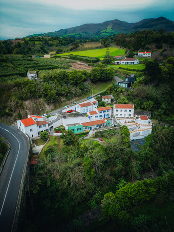 Aerial view of the quaint village nestled amidst verdant hills and lush vegetation with its vibrant rooftops contrasting against the deep green foliage Agua de Alto Azores Portugal.