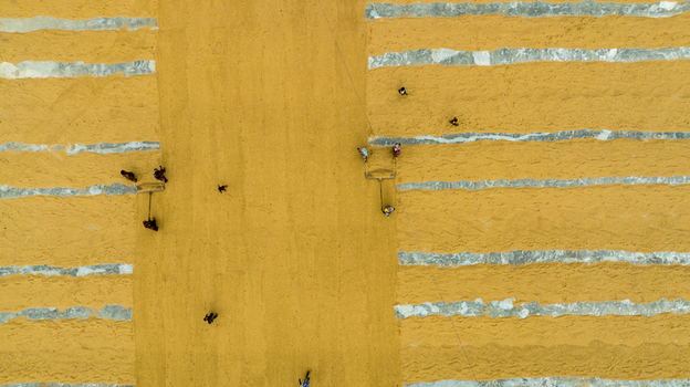Ashuganj Chittagong Division Bangladesh 05 July 2022 Aerial view of workers spreading and drying golden rice grains on a large concrete surface.