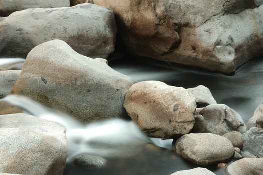 View of Sequoia National Park featuring smooth granite boulders and silky flowing water in a mountain stream Tulare County California United States. View of Sequoia National Park featuring smooth granite boulders and silky flowing water in a mountain stream Tulare County California United States.