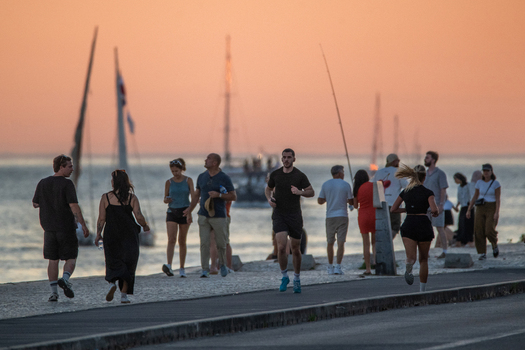 Lisbon Lisbon Portugal 13 September 2026 View of people walking and jogging along the waterfront promenade at sunset with sailboats on the Tagus River. Lisbon Lisbon Portugal 13 September 2026 View of people walking and jogging along the waterfront promenade at sunset with sailboats on the Tagus River.