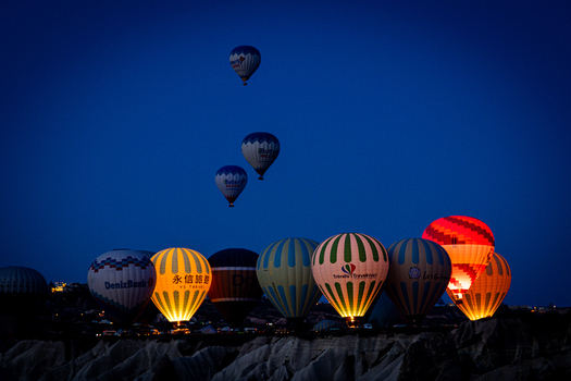 Goreme Turkiye 07 April 2025 Aerial view of colorful hot air balloons glowing against the dark blue twilight sky over the unique volcanic landscape of Cappadocia. Goreme Turkiye 07 April 2025 Aerial view of colorful hot air balloons glowing against the dark blue twilight sky over the unique volcanic landscape of Cappadocia.