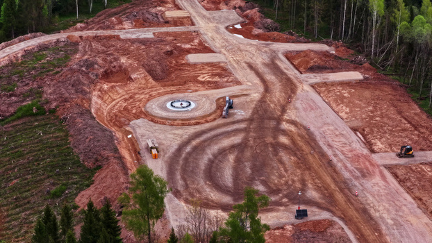 Aerial view of wind turbine foundation construction site with cleared earth tire tracks and surrounding forest in Latvia. Aerial view of wind turbine foundation construction site with cleared earth tire tracks and surrounding forest in Latvia.