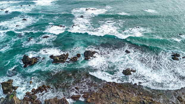 Aerial view of rocky coastline with crashing waves and turquoise water in Indonesia. Aerial view of rocky coastline with crashing waves and turquoise water in Indonesia.