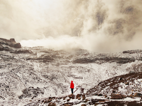 Aerial view of a person in a red jacket standing on the snow covered slopes of Volcano Chimborazo in the Andes mountains Guano Chimborazo Ecuador. Aerial view of a person in a red jacket standing on the snow covered slopes of Volcano Chimborazo in the Andes mountains Guano Chimborazo Ecuador.
