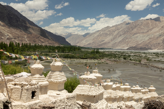 View of Charasa Gonpa with white stupas and prayer flags overlooking the river valley and mountains in Charasa Ladakh India.