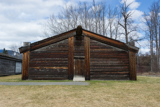 View of a traditional Gitxsan longhouse with carved wooden logs and a central entrance at the Ksan Historical Village in Ksan British Columbia Canada. View of a traditional Gitxsan longhouse with carved wooden logs and a central entrance at the Ksan Historical Village in Ksan British Columbia Canada.