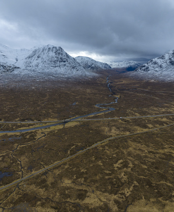 Aerial view of River Etive Bridge crossing a winding river amidst snow capped mountains and vast moorland in Ballachulish Scotland United Kingdom. Aerial view of River Etive Bridge crossing a winding river amidst snow capped mountains and vast moorland in Ballachulish Scotland United Kingdom.