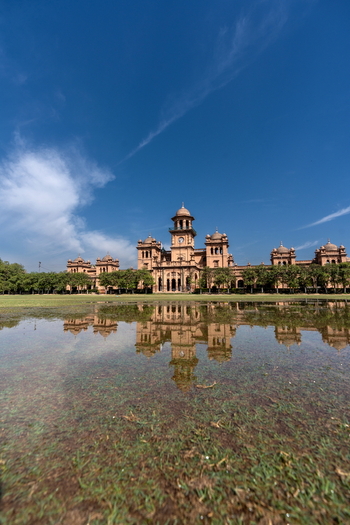 View of the historic Islamia College University building reflected in a large puddle on the grassy lawn under a clear blue sky in Peshawar Khyber Pakhtunkhwa Pakistan. View of the historic Islamia College University building reflected in a large puddle on the grassy lawn under a clear blue sky in Peshawar Khyber Pakhtunkhwa Pakistan.