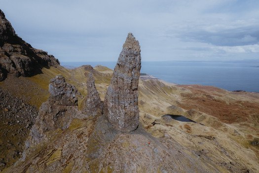 Aerial view of The Storr a dramatic basalt rock formation on the Isle of Skye featuring rugged cliffs grassy slopes and the sea in the background Portree Scotland United Kingdom. Aerial view of The Storr a dramatic basalt rock formation on the Isle of Skye featuring rugged cliffs grassy slopes and the sea in the background Portree Scotland United Kingdom.
