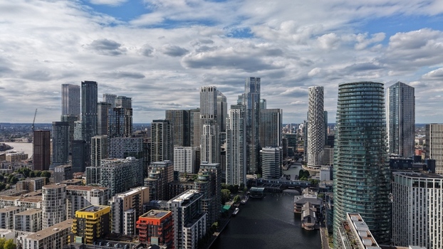 London United Kingdom 16 June 2026 Aerial view of Canary Wharf financial district featuring modern skyscrapers the River Thames and residential blocks under a cloudy sky.