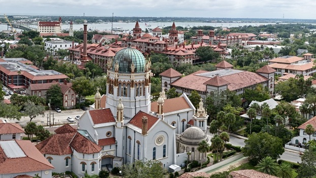 Aerial view of Memorial Presbyterian Church with its copper dome and terracotta roof tiles surrounded by historic buildings and lush greenery in St. Augustine Florida United States.