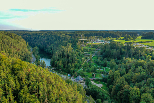 Aerial view of Skywalk Pottenstein and the summer toboggan run surrounded by dense green forests and a winding river in Pottenstein Bayern Germany. Aerial view of Skywalk Pottenstein and the summer toboggan run surrounded by dense green forests and a winding river in Pottenstein Bayern Germany.