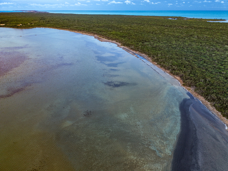 Aerial view of Salt Pond featuring turquoise water and lush green vegetation along the tropical coastline in Exuma Exuma The Bahamas.