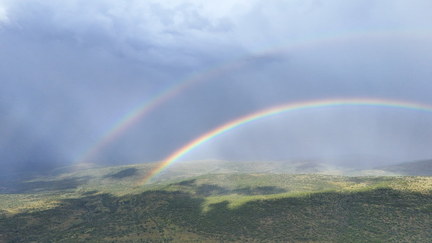 Aerial view of a double rainbow arching over the green hills and valleys of the Waterberg region under a dramatic stormy sky Waterberg District Municipality Limpopo South Africa. Aerial view of a double rainbow arching over the green hills and valleys of the Waterberg region under a dramatic stormy sky Waterberg District Municipality Limpopo South Africa.
