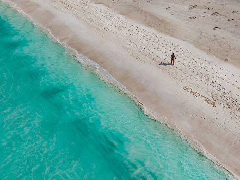 Aerial view of turquoise waters kissing the powdery sands of Shoab Beach a solitary figure adds scale to the vast untouched beauty Shoab beach Socotra Yemen. Aerial view of turquoise waters kissing the powdery sands of Shoab Beach a solitary figure adds scale to the vast untouched beauty Shoab beach Socotra Yemen.