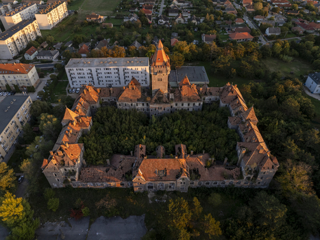 Aerial view of the abandoned Hajmasker Barracks with its overgrown courtyard and historic red tiled roofs illuminated by golden hour light in Hajmasker Hungary. Aerial view of the abandoned Hajmasker Barracks with its overgrown courtyard and historic red tiled roofs illuminated by golden hour light in Hajmasker Hungary.