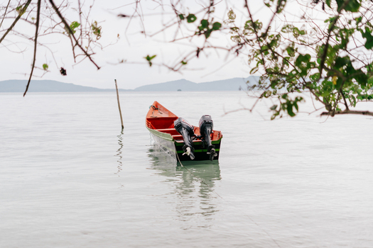View of a small wooden boat with outboard motors floating in the calm turquoise waters of Raja Ampat Southwest Papua Indonesia.