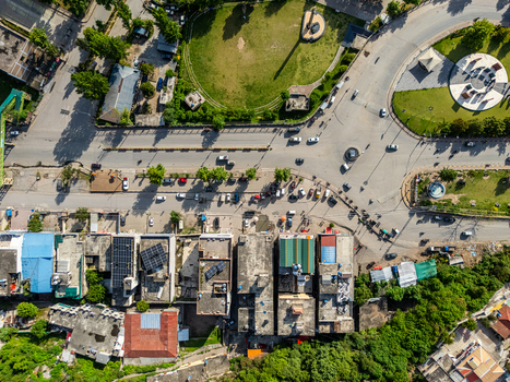 Aerial view of a busy roundabout and road intersection featuring urban buildings parked vehicles and green spaces in Muzaffarabad Azad Kashmir Pakistan. Aerial view of a busy roundabout and road intersection featuring urban buildings parked vehicles and green spaces in Muzaffarabad Azad Kashmir Pakistan.