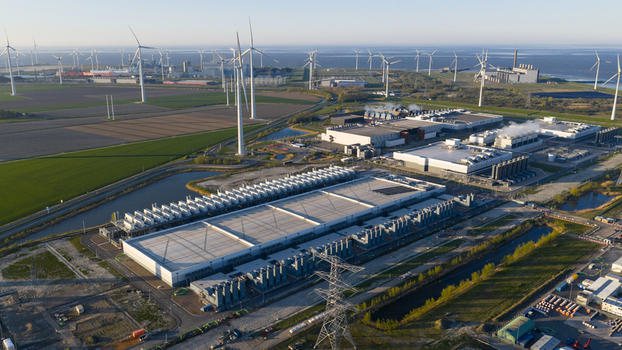 Aerial view of a large industrial data center facility and wind farm under a clear sky in Eemshaven Groningen Netherlands. Aerial view of a large industrial data center facility and wind farm under a clear sky in Eemshaven Groningen Netherlands.