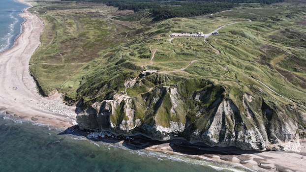 Aerial view of Bulbjerg a prominent limestone cliff formation on the coast of Jutland featuring rugged slopes grassy terrain and a sandy beach in Thisted Municipality Denmark. Aerial view of Bulbjerg a prominent limestone cliff formation on the coast of Jutland featuring rugged slopes grassy terrain and a sandy beach in Thisted Municipality Denmark.