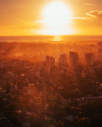 Chattogram Chittagong Division Bangladesh 01 September 2021 Aerial view of the city skyline at sunset with building silhouettes and lush trees glowing in warm golden light.