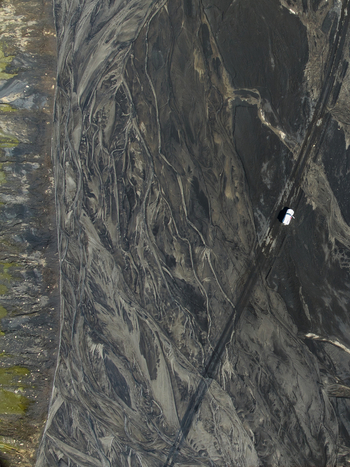 Aerial view of a white vehicle driving on a dark volcanic ash road through a vast textured landscape of black sand and glacial river patterns Kirkjubaejarklaustur Skaftarhreppur Iceland. Aerial view of a white vehicle driving on a dark volcanic ash road through a vast textured landscape of black sand and glacial river patterns Kirkjubaejarklaustur Skaftarhreppur Iceland.