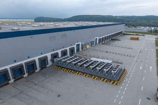 Aerial view of a modern logistics hub with loading docks industrial cooling units and a large paved yard in Skawina Lesser Poland Voivode Poland. Aerial view of a modern logistics hub with loading docks industrial cooling units and a large paved yard in Skawina Lesser Poland Voivode Poland.