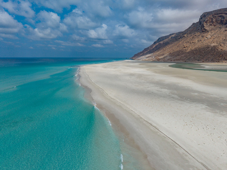 Aerial view of the turquoise lagoon meeting the stark white sands contrasting with the rugged rocky coastline Detwah lagoon Socotra Yemen.