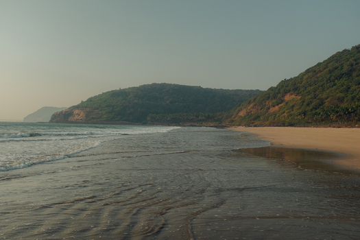 View of tranquil waves gently kissing the golden sands beneath verdant hills under a serene sky in Chiplun Maharashtra India Chiplun Maharashtra India. View of tranquil waves gently kissing the golden sands beneath verdant hills under a serene sky in Chiplun Maharashtra India Chiplun Maharashtra India.