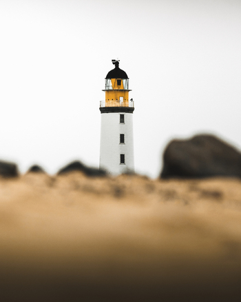 View of picturesque lighthouse on rocky coastline with tranquil sea and sandy beach Crimond Great Britain.