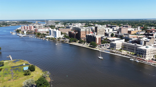 Aerial view of the Cape Fear River waterfront in downtown featuring historic buildings boats on the water and a clear blue sky in Wilmington North Carolina United States.