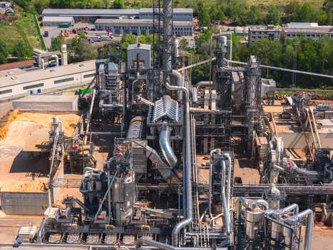 Aerial view of an industrial wood processing facility with complex piping metal structures and piles of sawdust in Jihlava Vysocina Region Czechia.