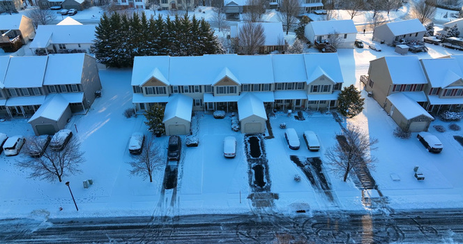 Aerial view of a suburban street featuring rows of townhouses covered in fresh snow with snow covered driveways and cars under a clear winter sky in Manheim Pennsylvania United States. Aerial view of a suburban street featuring rows of townhouses covered in fresh snow with snow covered driveways and cars under a clear winter sky in Manheim Pennsylvania United States.
