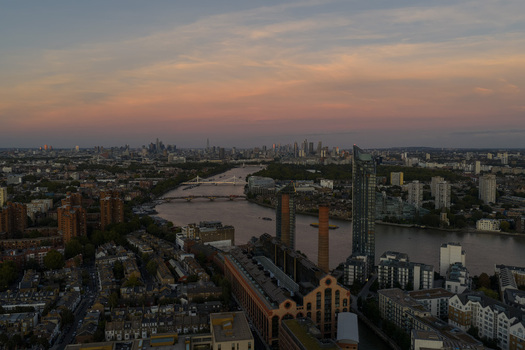 Aerial view of Lots Road Power Station and the River Thames with bridges and the city skyline under a sunset sky in London England United Kingdom. Aerial view of Lots Road Power Station and the River Thames with bridges and the city skyline under a sunset sky in London England United Kingdom.