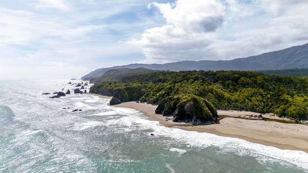Aerial view of the rugged coastline where the lush green forest meets the crashing waves Ship Creek Haast West Coast Region New Zealand. Aerial view of the rugged coastline where the lush green forest meets the crashing waves Ship Creek Haast West Coast Region New Zealand.