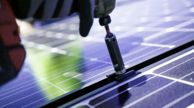View of a solar installer securing a photovoltaic panel with a power drill in Los Angeles CA United States.
