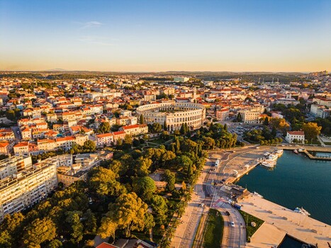 Aerial view of the iconic Pula Arena standing proudly amidst the urban tapestry where terracotta rooftops meet the azure Adriatic Pula Istria County Croatia.
