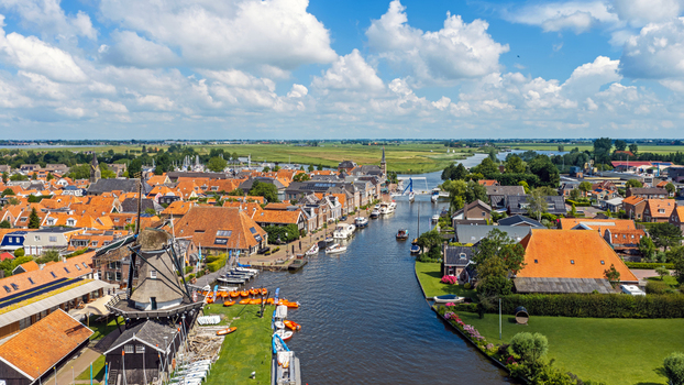 Aerial view of a traditional windmill overlooking the canal and historic orange tiled rooftops of the village of Woudsend Friesland Netherlands. Aerial view of a traditional windmill overlooking the canal and historic orange tiled rooftops of the village of Woudsend Friesland Netherlands.