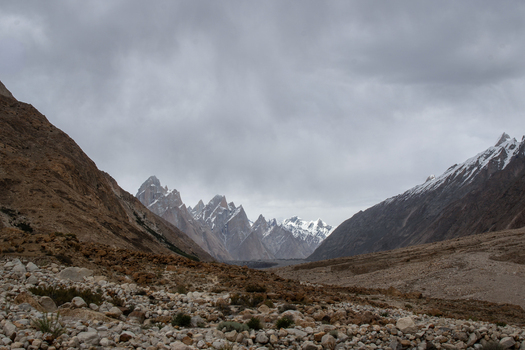 View of K2 Base Camp featuring rugged rocky terrain and towering snow capped peaks under a dramatic cloudy sky in the Karakoram mountain range Gilgit Pakistan. View of K2 Base Camp featuring rugged rocky terrain and towering snow capped peaks under a dramatic cloudy sky in the Karakoram mountain range Gilgit Pakistan.